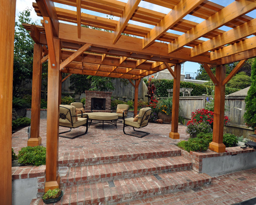 Twin cedar arbors define brick-lined patios that lead to a romantic outdoor fireplace.  The warm colors of the cedar and brick compliment the deep brown newly painted home, with pops of color from the trees, bushes and plants surrounding it