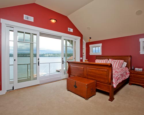 An expansive master suite with lake views and oversized doors to a balcony overlooking the waterfront