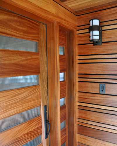 Linear art crafted from mahogany. The alternating widths provide visual interest and tie in with the horizontal sidelite and door panels. Reeded glass lets in light and maintains privacy in this Seattle home entry remodel