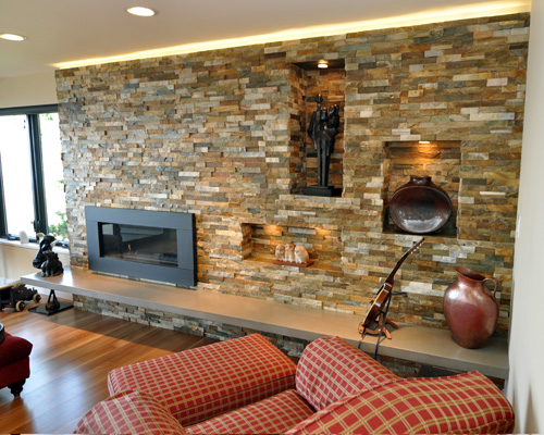 The floating hearth is cast concrete and the surround is quartzite, with puc-lit niches.  The hearth is engineered to double as a seating area while entertaining, and tape light along the top edge of the quartzite surround illuminates the ceiling