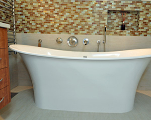 Where a dated vanity once stood there is now an elegant Victoria + Albert soaking tub with a niche and hand-held faucet