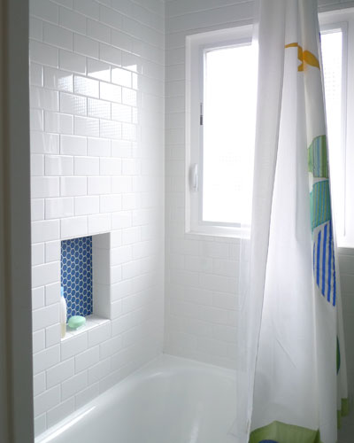 The blue accents continue in the kids bathroom surround.  The niche is a deep blue hex tile.  The balance is simple subway tile.  The hexagon tile bathroom on the floor also has integrated blue tile flowers in this kids bath Seattle