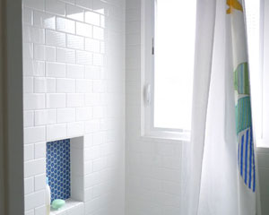 The blue accents continue in the kids bathroom surround.  The niche is a deep blue hex tile.  The balance is simple subway tile.  The hexagon tile bathroom on the floor also has integrated blue tile flowers in this kids bath Seattle