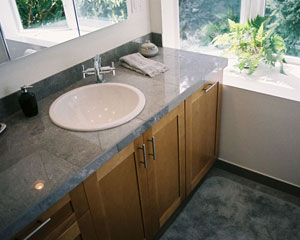A new vanity with porcelain tile counters and Grohe faucet integrates into the tile work at the adjacent shower niche