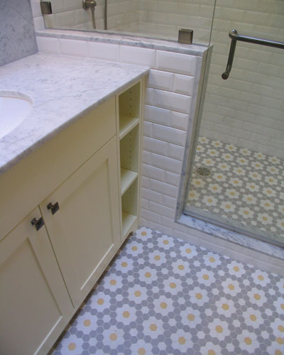 The old-fashioned tile compliments the Carrera marble counters'pillow-style subway tile and flowery hexagon floor tile, hexagon tile bathroom