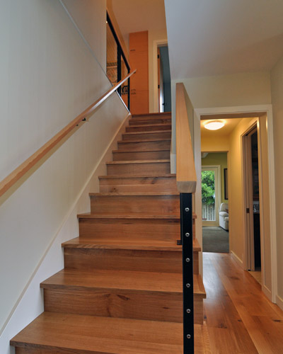 Now steel stringer railings with fir caps grace the stairs, and knotty oak treads lead the way upstairs.  At the top left side of the stairs, a planned wall was removed mid-project to allow for a wall to display family photos