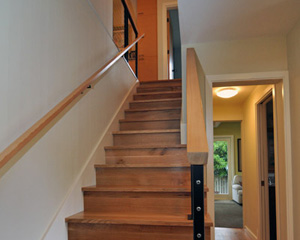 Now steel stringer railings with fir caps grace the stairs, and knotty oak treads lead the way upstairs.  At the top left side of the stairs, a planned wall was removed mid-project to allow for a wall to display family photos