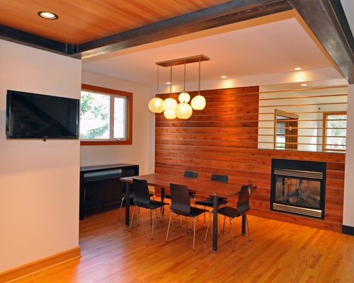 That boring dining room is no more. The horizontal cedar and fir on the fireplace wall warm up the room, and integrate the two-sided fireplace into the room