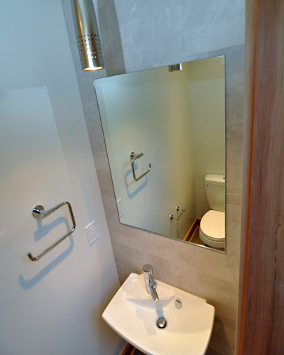 A small sink and mirror is tucked into the other side on a wall clad with marble subway tile