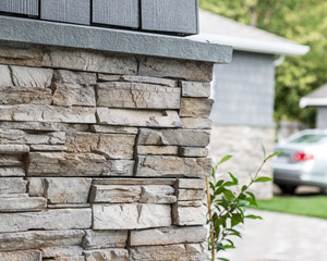 Siding is specially painted James Hardie shingles installed randomly for a beachy look, with blue stone sills as a belly band between the shingles and stacked stone.  The blue stone also serves as the sill for all of the windows