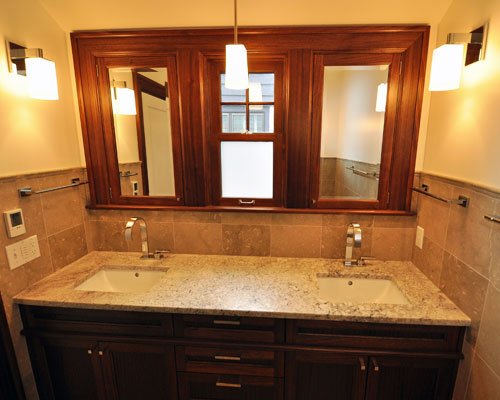 The revised vanity area is symmetrical and beautiful, with traditional trim and cabinetry, and chrome Dornbracht faucets to bring some modern interest.  Note the controls to the left, which include a programmable thermostat for the heat mat under the tile