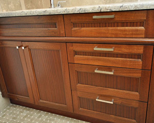 The custom vanity, built by Pete's Cabinets, is made of mahogany and book-matched to show off the exceptional grain.  A continuous trim piece between the upper and lower sections of the cabinet lends simple elegance