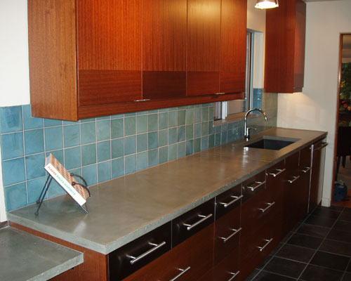 A deep single composite sink blends in because of its dark color.  A new window with a sill in the same material as the countertop helps with ventilation in the kitchen, Seattle custom kitchen cabinet